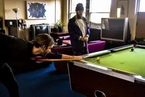Two friends playing on the pool table in the living room after the pool table relocation