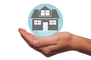 a hand holding a house model in a blue bubble