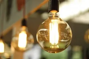 A close up of a light bulb. The rest of the photo is blurred, but we can see some more light bulbs in the background. 