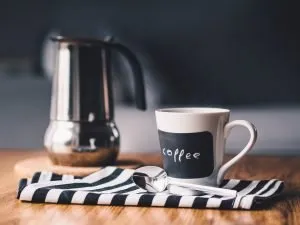 A cup of coffee next to a pot.