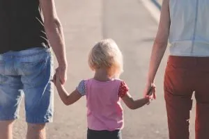 Parents holding a girl's hands.