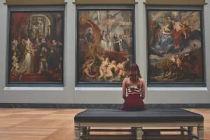 A woman sitting in front of artwork in one of the top museums in Miami to visit.