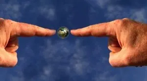 Two fingers a pointing to a small planet Earth