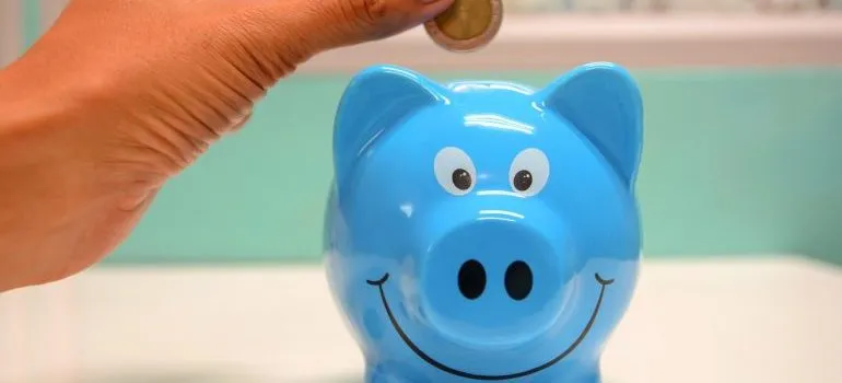 someone putting a coin into a blue piggy bank