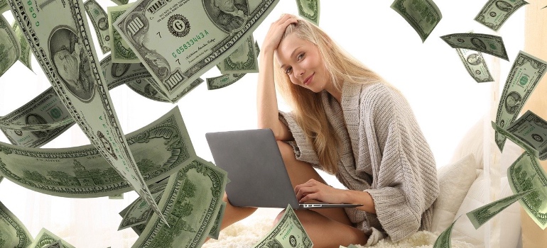 A girl with a laptop and dollar bills 
