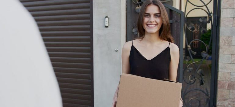 A happy girl carrying moving box