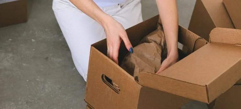 a woman packing a wrapped thing in a box
