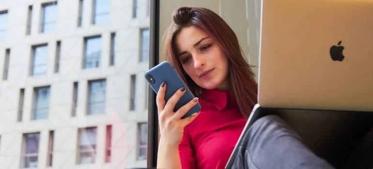 A woman holding a laptop and a phone.