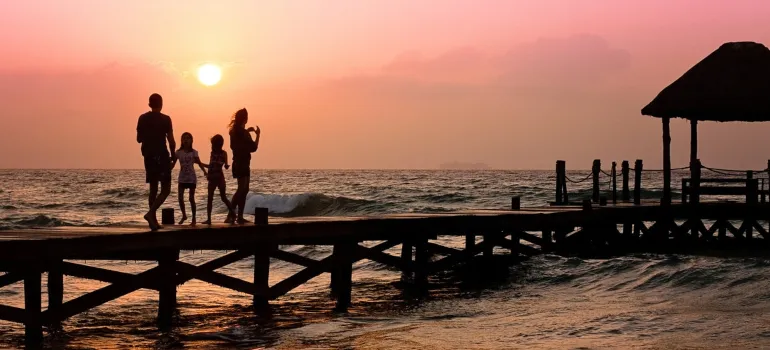 a family of four walking on a dock during the sunset