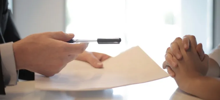 A man holds a contract for signing and a pen.