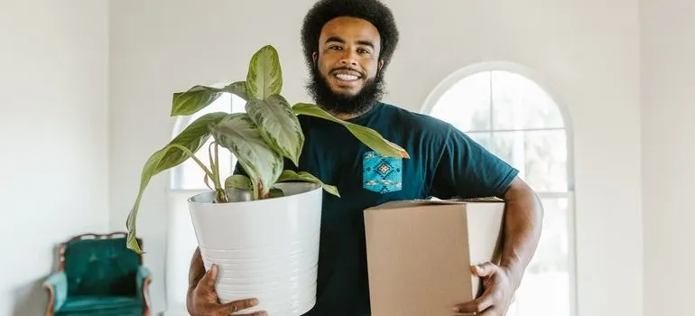 Deerfield Beach mover holding a plant and a box