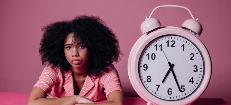 a woman laying beside a giant pink clock