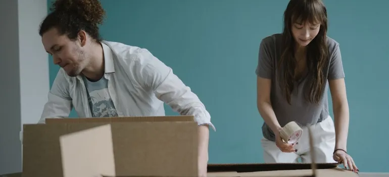 a man and a woman packing things into cardboard boxes