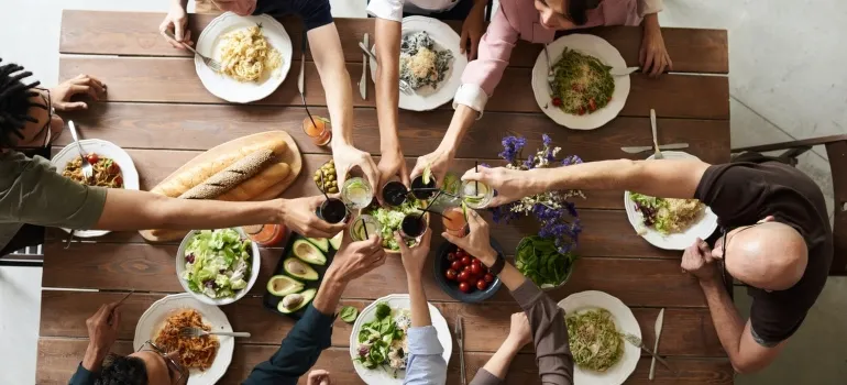 group of friends gathered around a table with food, making a toast