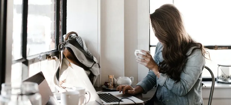 woman drinking coffee and typing on her computer